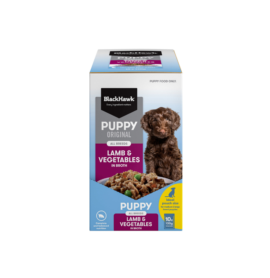 A box of BlackHawk Puppy Original Lamb & Vegetables in Broth dog food, featuring a white, blue, and purple packaging design with a picture of a brown puppy on the front.
