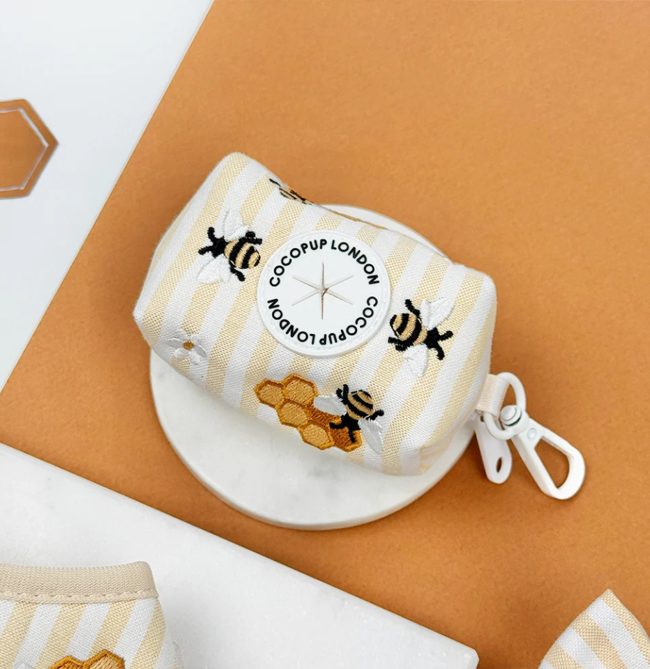 Cocopup London Honey Meadow poop bag holder, yellow and white stripes with embroidered bees and honey pots in a brown and white background