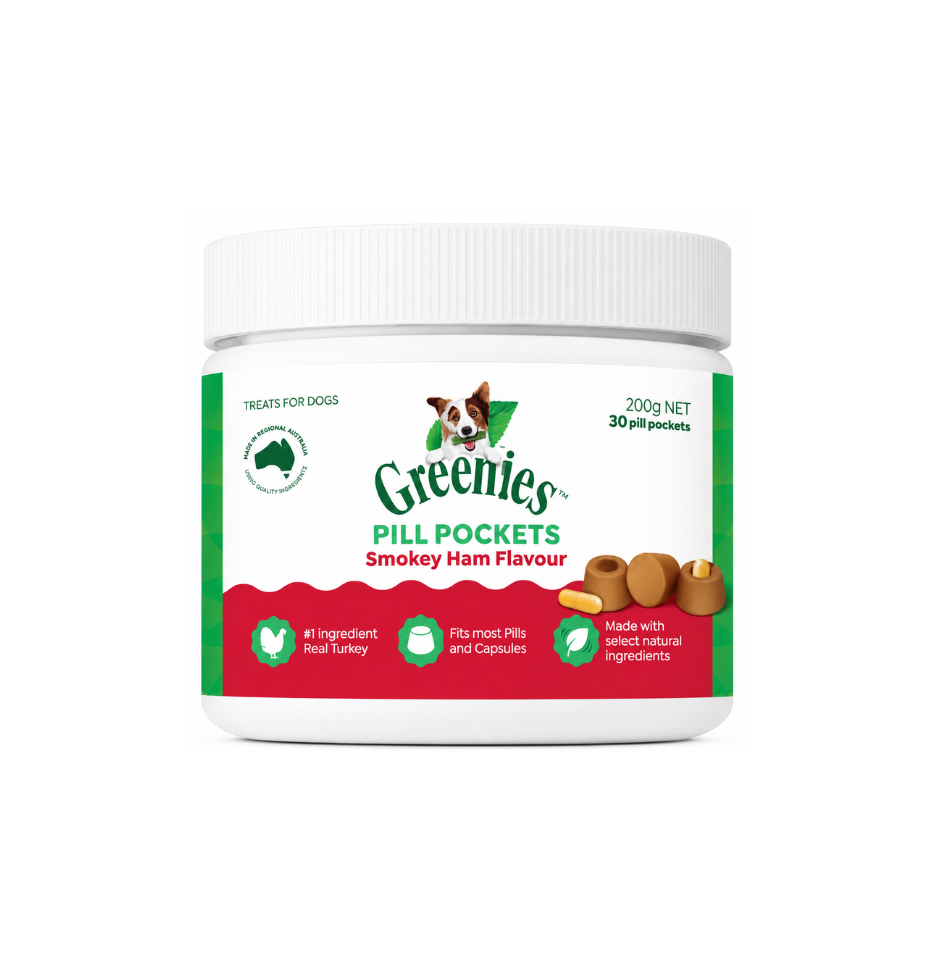 A white plastic jar of Greenies Pill Pocket dog treats in Smokey Ham Flavour, featuring a white lid and a label with green and red sections, on a plain white background.