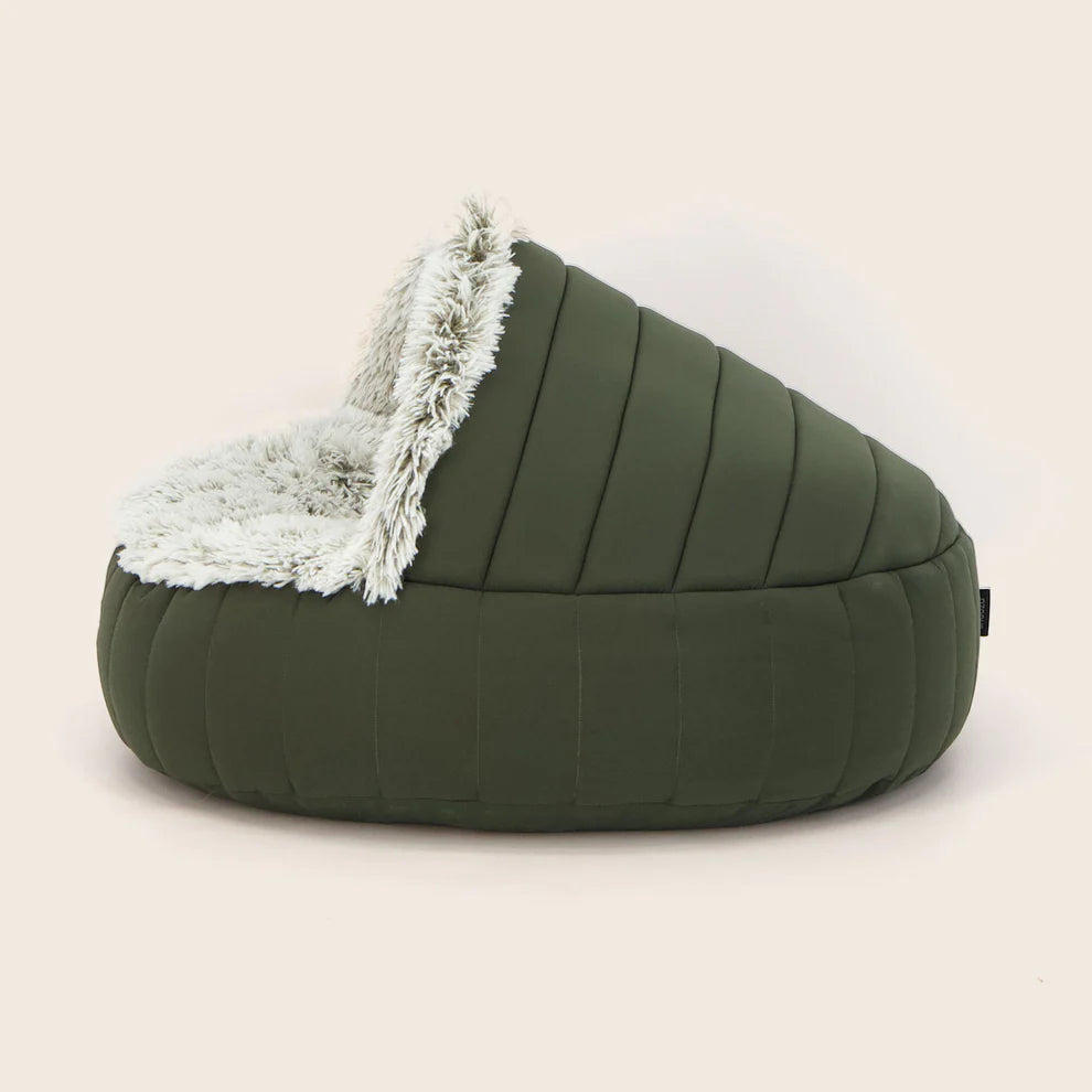 Green Snooza dog bed with white fur lining on a beige background
