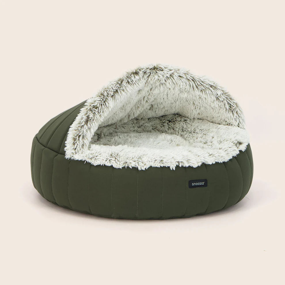 Green snooza dog bed with fluffy white interior on a beige background